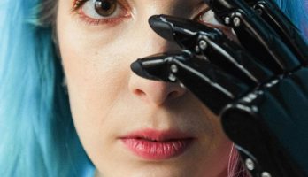 Close-up portrait of a woman with colored hair and a prosthetic hand